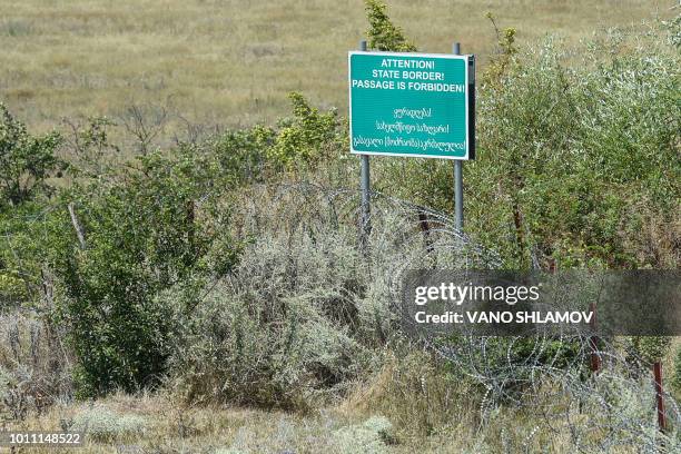 Picture taken on July 25, 2018 shows a warning sign behind a wire barricade erected by Russian and Ossetian troops along Georgia's de-facto border...