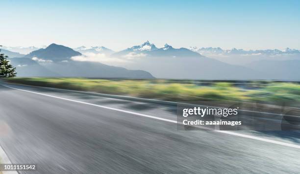 blurred motion country road toward snow mountains - land speed stockfoto's en -beelden