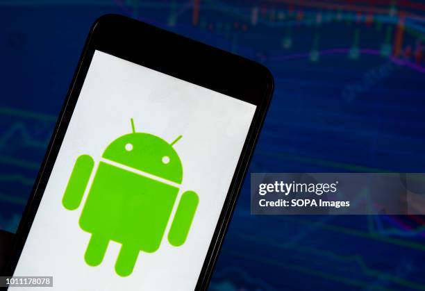 In this photo illustration, the Android application seen displayed on a smartphone with a background of a stock market. Android is a mobile operating...