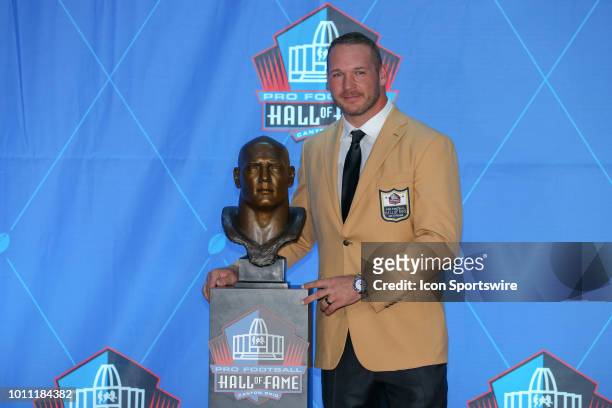 Brian Urlacher poses for photographers next to his Hall of Fame bust after he was enshrined into the Pro Football Hall of Fame during the 2018 Pro...