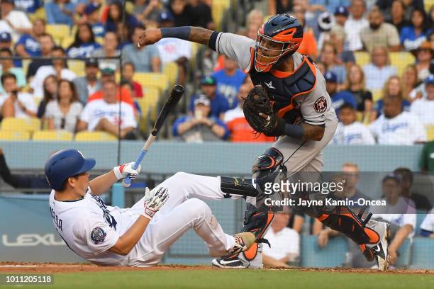 Kenta Maeda of the Los Angeles Dodgers falls on the ground after a swinging strike as Martin Maldonado of the Houston Astros throws out Austin Barnes...