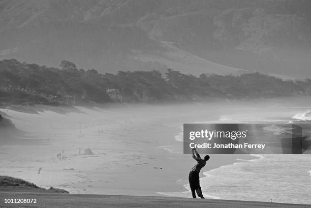 Tiger Woods of the United States silhouetted against the oceanside backdrop as he plays from the ninth fairway during the the 100th United States...