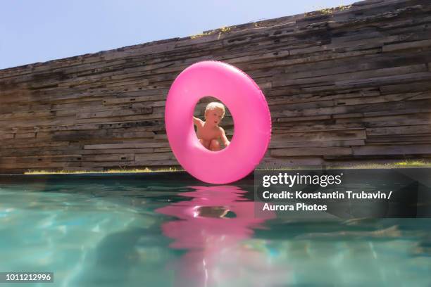 boy with inflatable ring near swimming pool - pink wall stock-fotos und bilder