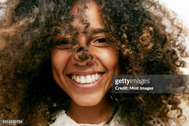 portrait of smiling young woman with brown curly hair, looking at camera. - hair curls photos et images de collection