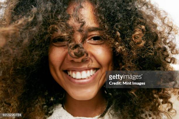 portrait of smiling young woman with brown curly hair, looking at camera. - gekruld haar stockfoto's en -beelden
