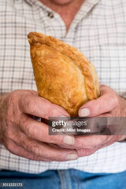 a man holding a fresh homemade pasty with a crimped edge, a regional speciality - blätterteigpastete stock-fotos und bilder