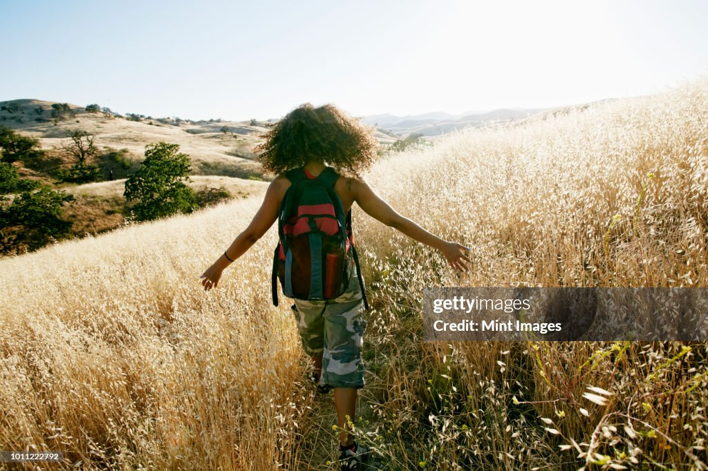 Young mixed race woman with curly brown hair hiking in urban park.