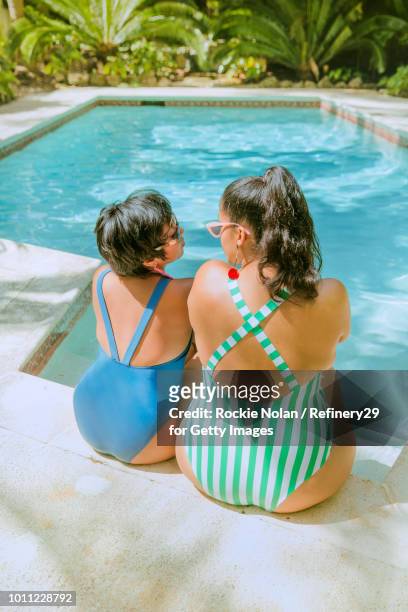 Two young confident women sitting by the pool