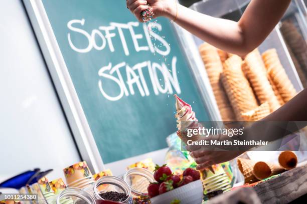 eis wird mit streusel bestreut - eis dekorieren an der softeis station - ice cream sprinkles stock pictures, royalty-free photos & images