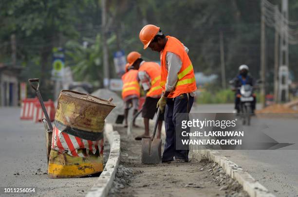 Sri Lankan road construction workers construction labourers works along a road in Colombo on August 5, 2018. - Sri Lanka's central bank on August 3...