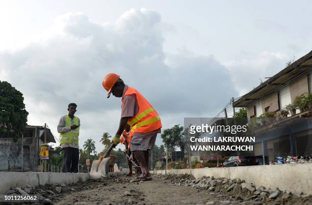 Sri Lankan road construction workers construction labourers works along a road in Colombo on August 5, 2018. - Sri Lanka's central bank on August 3...
