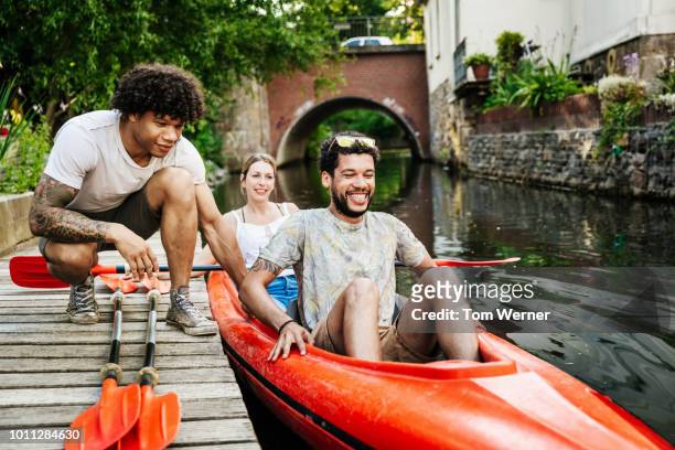 friends getting ready to go paddling in kayak - saksen stockfoto's en -beelden