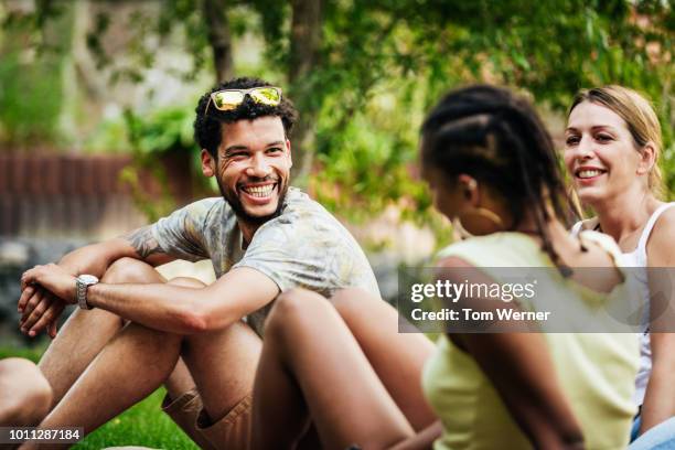 group of friends sitting down together in the sun - grupo de hombres fotografías e imágenes de stock