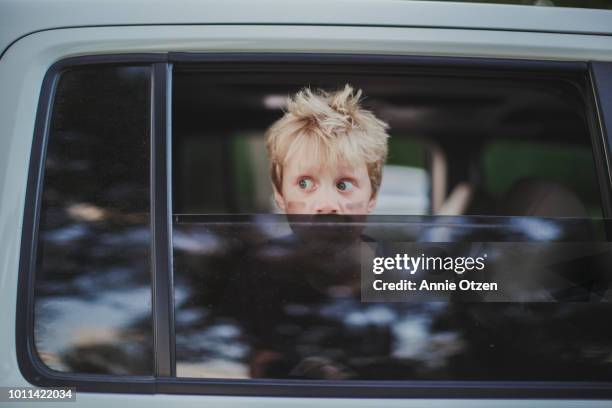 boy looking out partially opened car window - car window stockfoto's en -beelden