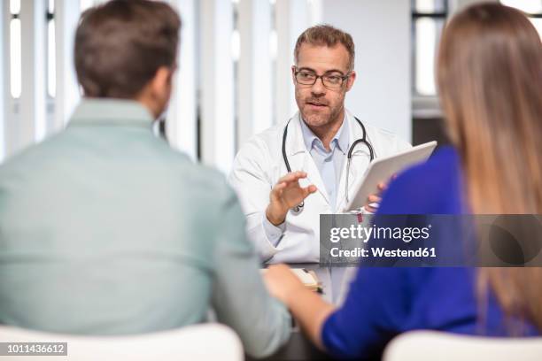 doctor talking to couple in medical practice - menschliche fruchtbarkeit stock-fotos und bilder
