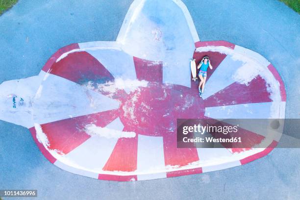 female longboarder with earphones lying in halfpipe - half pipe stock-fotos und bilder