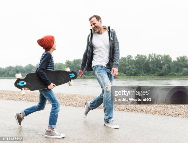 happy father and son with skateboard at the riverside - father longboard stock pictures, royalty-free photos & images