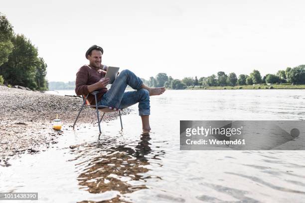 mature man using tablet at rhine riverbank - vivere semplicemente foto e immagini stock