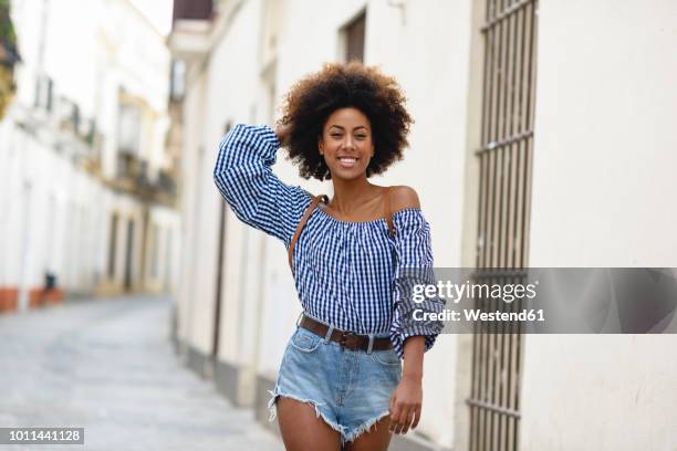 portrait of fashionable young woman with curly brown hair - women in daisy dukes stock-fotos und bilder