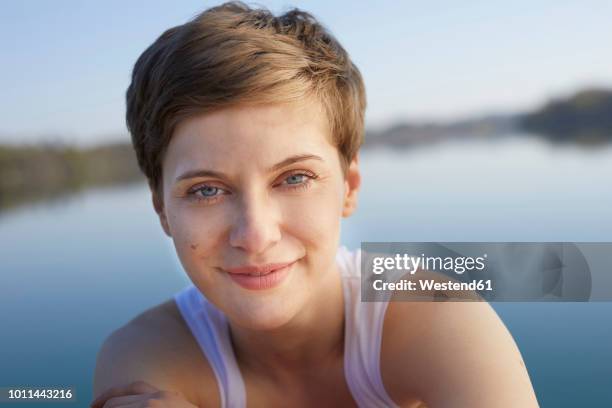 portrait of smiling woman in front of lake - brunette woman stock pictures, royalty-free photos & images