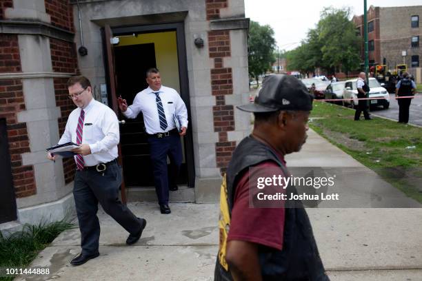 Bystander stands outside a crime scene where multiple people were shot and Chicago Police detectives exit an apartment building on Sunday, August 5,...