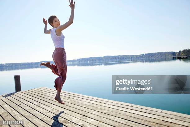 happy woman jumping in the air on jetty - see through clothing stock-fotos und bilder