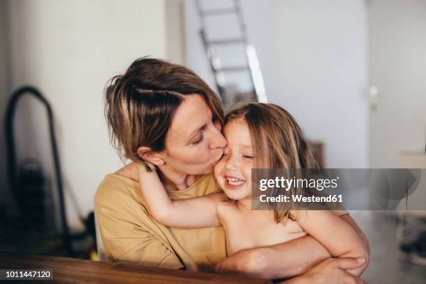 mother kissing her little daughter at new home - vorschulkind stock-fotos und bilder