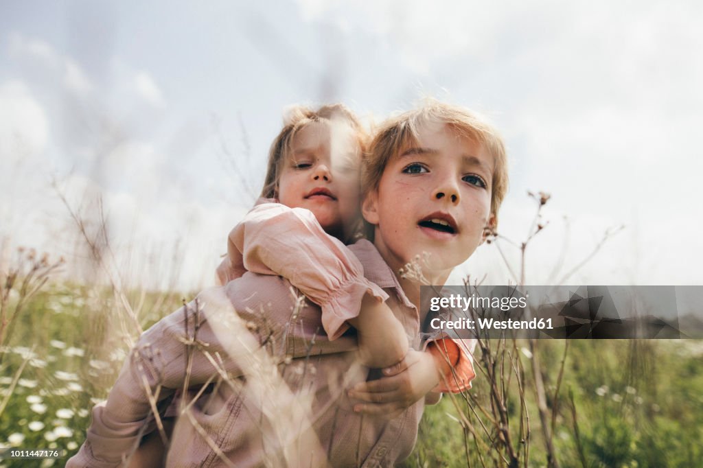 Portrait of boy giving his little sister a piggyback ride