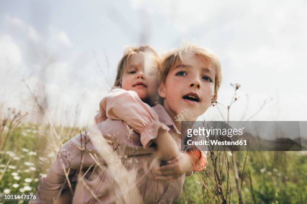 portrait of boy giving his little sister a piggyback ride - local girls - fotografias e filmes do acervo