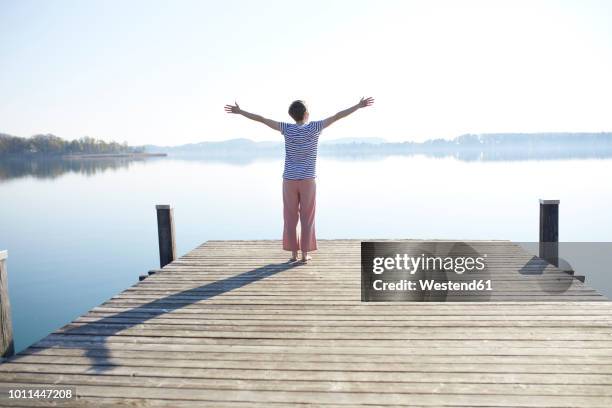 germany, bavaria, back view of woman standing on jetty at lake - boardwalk stockfoto's en -beelden