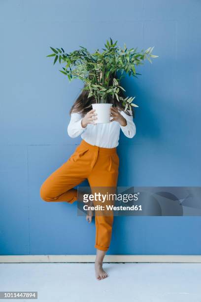 pretty young woman holding potted plant in front of her face - viso nascosto foto e immagini stock