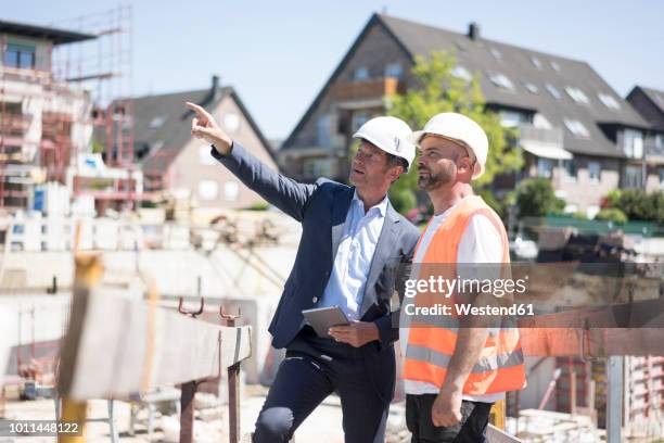 man in suit talking to construction worker on construction site - person in suit construction stock-fotos und bilder