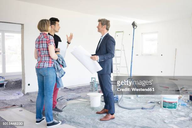 man in suit talking to couple in unfinished building - foundations conversations with suits stock-fotos und bilder