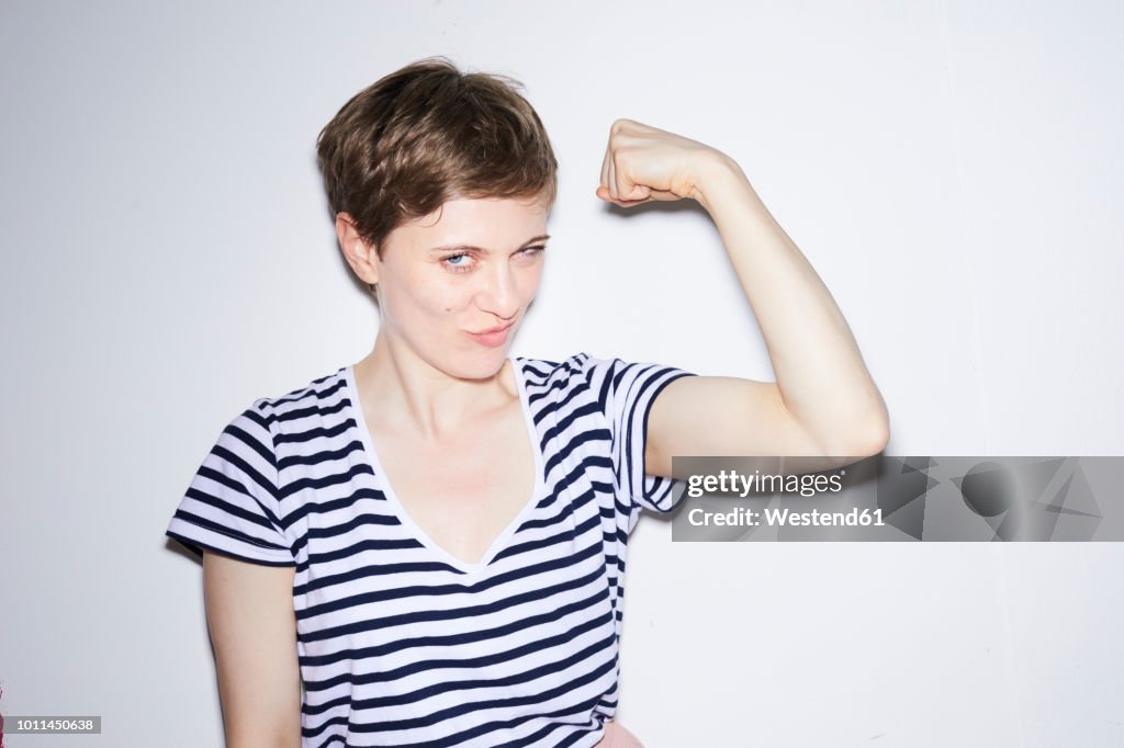 Portrait of blond woman, short hair, showing muscles