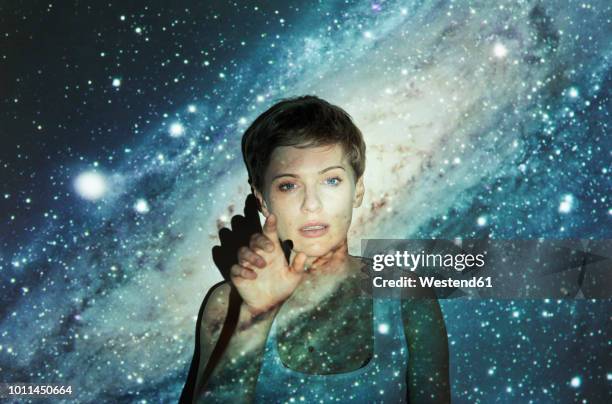 portrait of blond woman, projection of milky way, imaginary touchscreen - wunsch stock-fotos und bilder