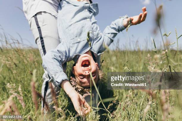 man carrying happy boy in a field - poträt mann frühling stock-fotos und bilder