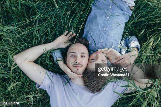 young man and boy lying in field - im gras liegen stock-fotos und bilder