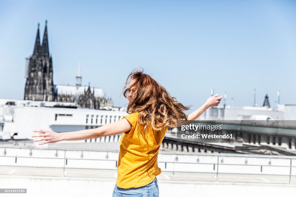 Germany, Cologne, woman dancing on roof terrrace
