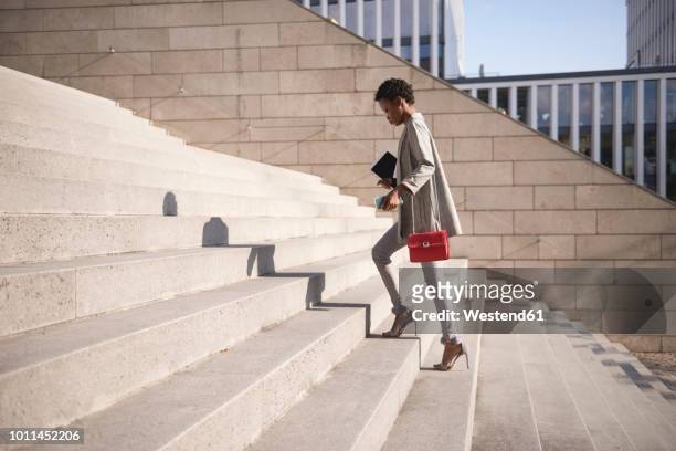businesswoman walking up stairs - handtasche stock-fotos und bilder