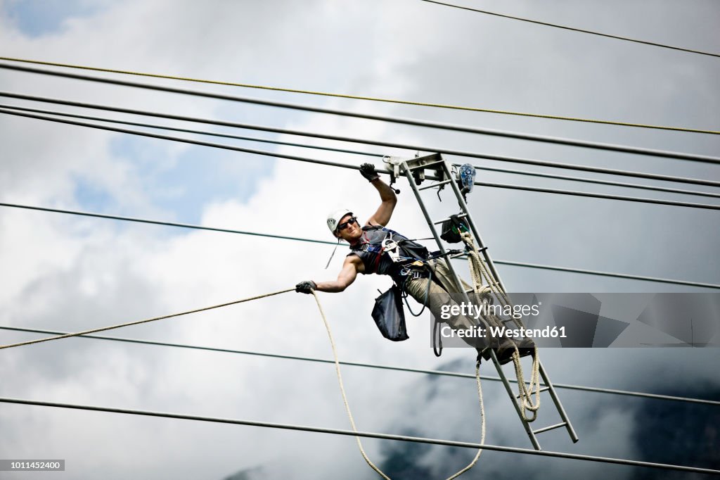 Fitter with ladder, pulling along high-voltage power line