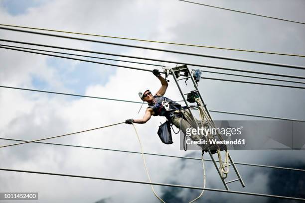 fitter with ladder, pulling along high-voltage power line - high voltage sign stock pictures, royalty-free photos & images