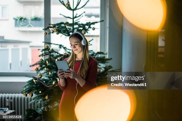 smiling woman using tablet and headphones at christmas time - christmas music listen stock pictures, royalty-free photos & images