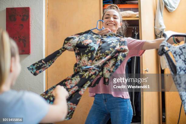 smiling teenage girl presenting clothes to her friend - girls getting ready imagens e fotografias de stock