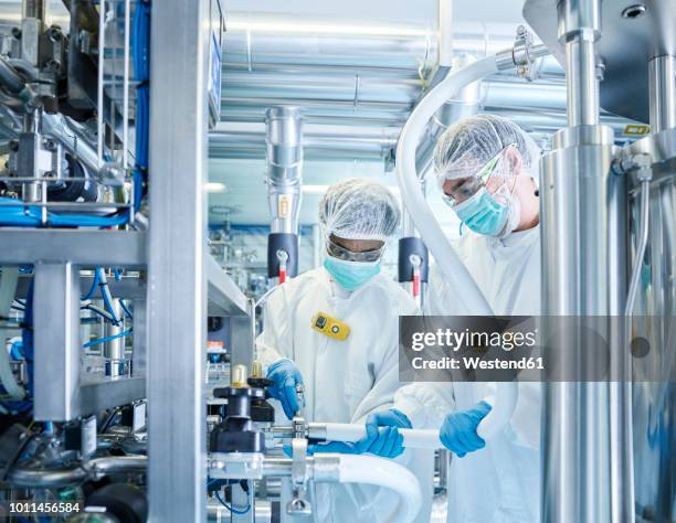 chemical laboratory technicians fitting hose - chemical factory stock pictures, royalty-free photos & images