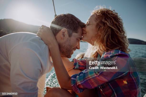affectionate couple with son on a sailing boat - kiss booth stock-fotos und bilder