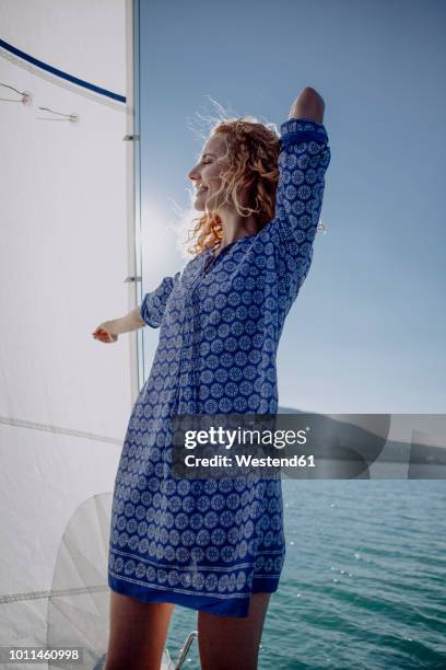 smiling woman standing on a sailing boat - women in see through dresses stock-fotos und bilder