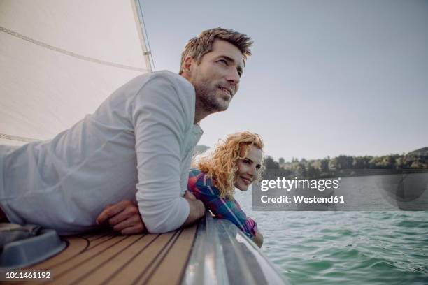 smiling couple relaxing on a sailing boat - couple boat stock pictures, royalty-free photos & images