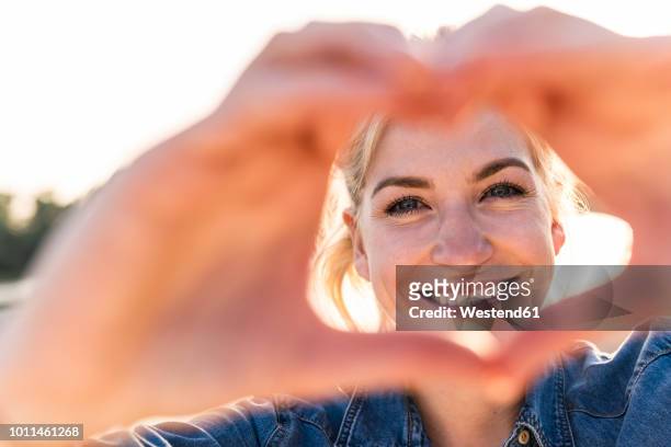 woman making heart shape with hands and fingers - woman in love stockfoto's en -beelden