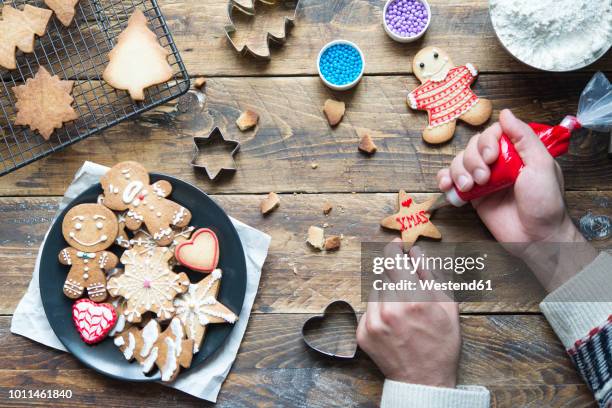 man's hand decorating christmas cookie - baked goods stock-fotos und bilder