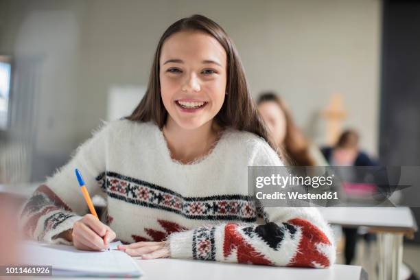 portrait of smiling teenage girl writing in exercise book in class - élève 12 ans photos et images de collection